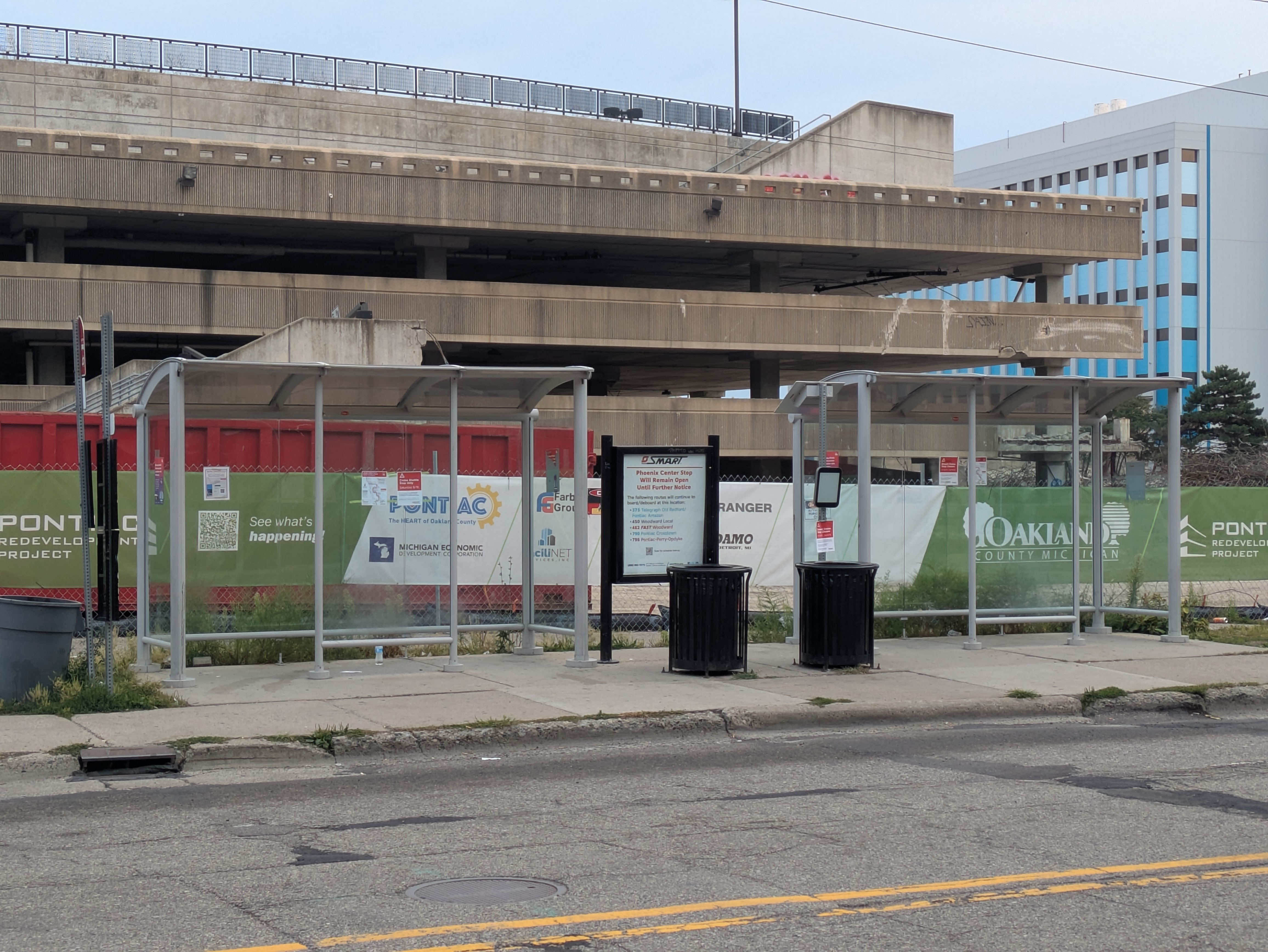 Two shelters on Water Street with a construction fence behind them for Phoenix Center demolition in 2025